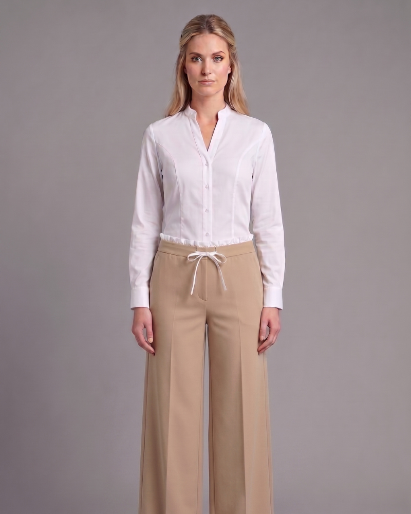 Trabajadora de Viding con uniforme de camisa blanca, pantalón beige de pierna ancha y zapatillas blancas.